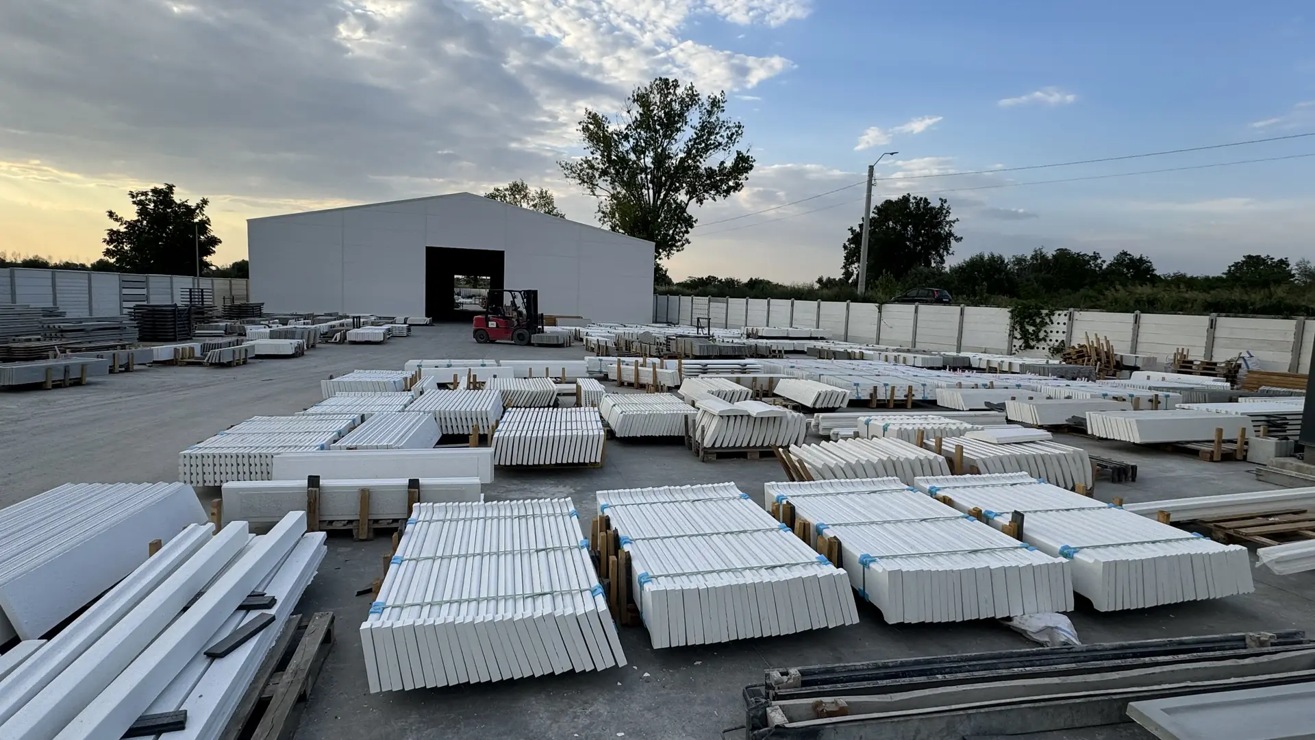 Dvor továrne Konkret Line v Măgurele podvečer – hotové dosky pred halou